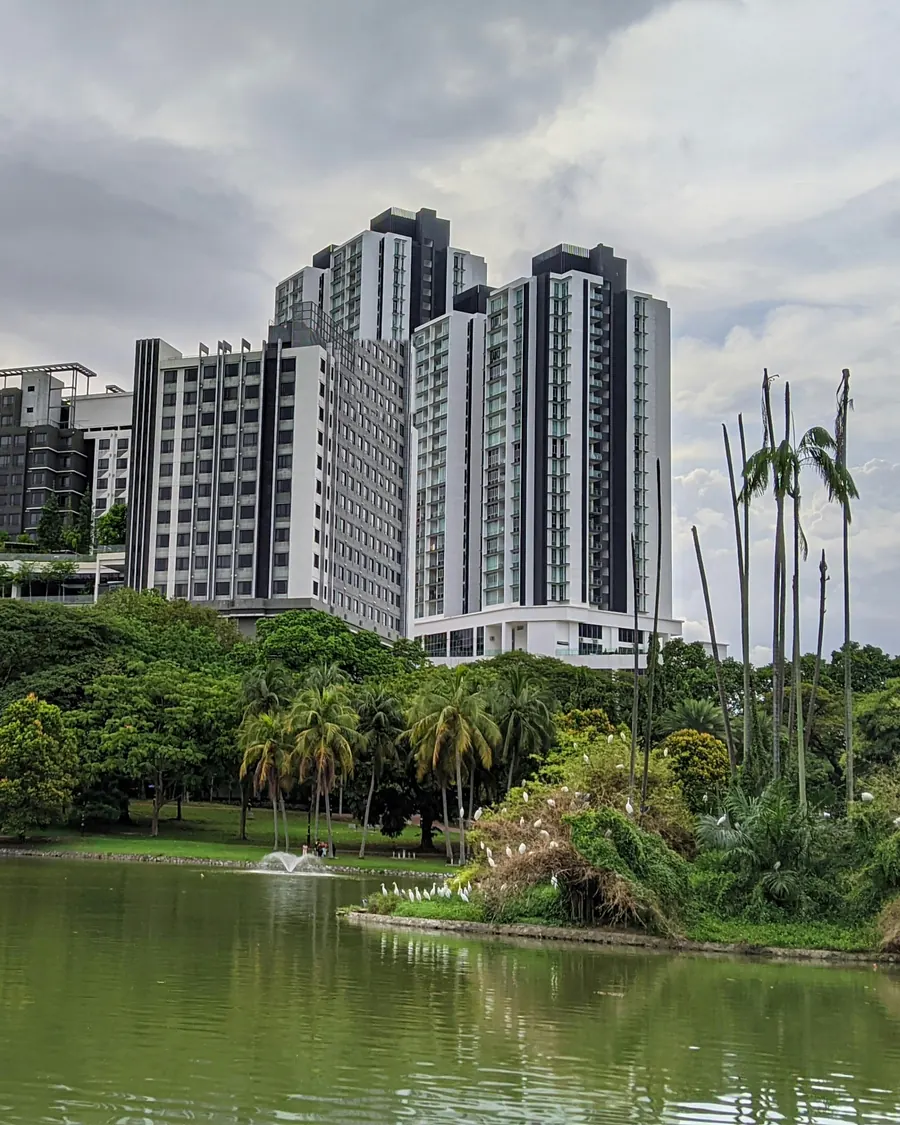 Condominium towers above a lake and tropical park on the edge of Mont Kiara