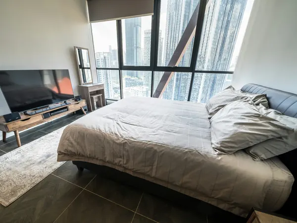 Studio with a queen bed and angled floor-to-ceiling windows