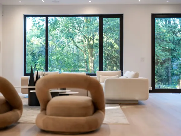 Living room with sculptural armchairs and a wall of windows onto trees
