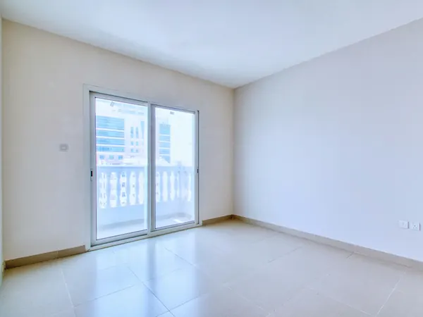 Empty bedroom with sliding doors to a balcony and city towers