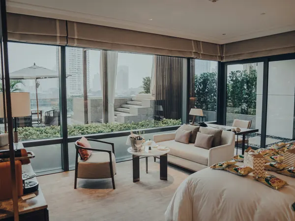 Open-plan suite with a lounge, bed and glass doors to a green terrace